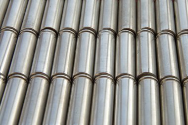 Parlak gümüş çelik silindirik yüzeyi olan metal parçalar. Parçalanmış lityum iyon faktör hücresi 2170 pil görüntüsü. Seçici odaklı soyut sanayi geçmişi.