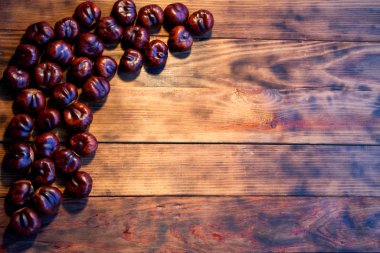 Kahverengi, yenilebilir at kestanesi. Koyu, ahşap bir arka planda, yazı için boşluk, üst manzara. Sonbahar dokusu, Şükran Günü konsepti.