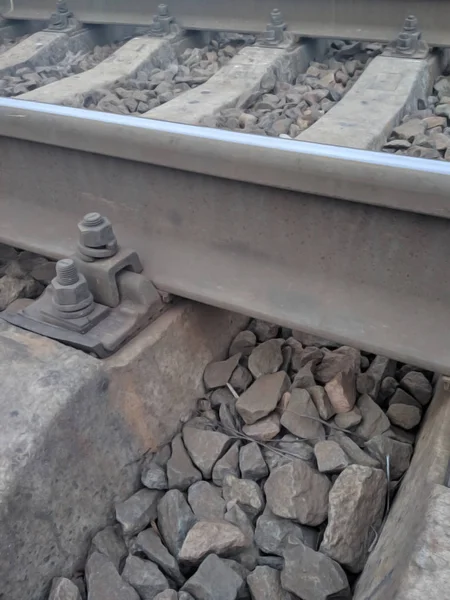 Vista em parafusos de fixação de trilhos ferroviários para laços cruzados de concreto. Parafusos enferrujados e velhos e porcas para fixação de trilho e dormentes. Os caminhos-de-ferro existentes. Desfocado . — Fotografia de Stock