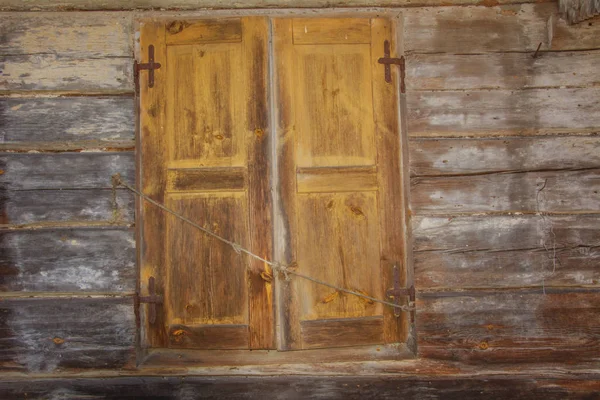 Old window with shutters closed. Abandoned wooden house on the outskirts. — Stock Photo, Image