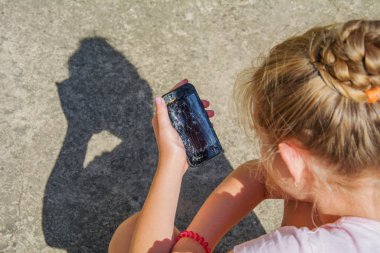 Üzgün genç kız elinde kırık cam ekranlı siyah, modern akıllı telefonu tutuyor..