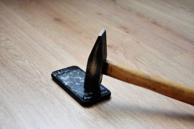 Büyük siyah demir çekiçle kırılmış bir cep telefonu ekranı. LCD ekran bozuk, kırılmış ve kullanılamaz akıllı telefon. Çekiç Ezici Cep Telefonu.