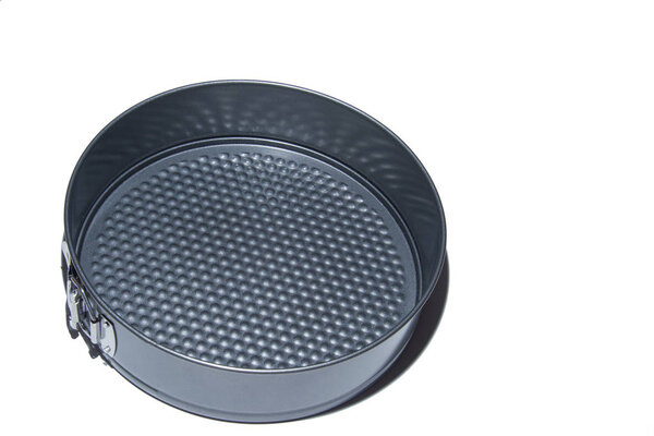 Homemade cake making or baking. Round metal cake pan, tin for baking cakes and cookies. Black collapsible stainless steel round cooking empty pan for cupcakes isolated on white background.