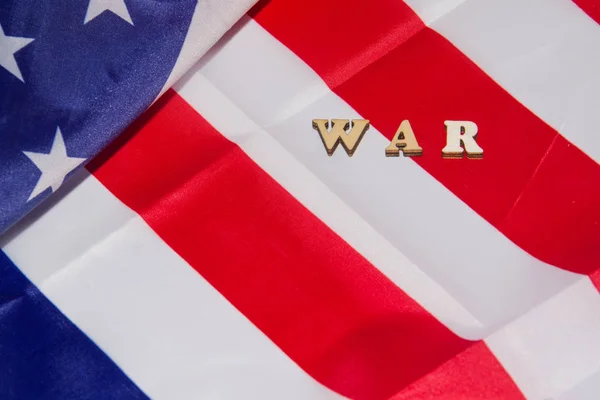 Слова WAR лежали деревянными буквами на фоне флага США. Концепция военной мощи США — стоковое фото