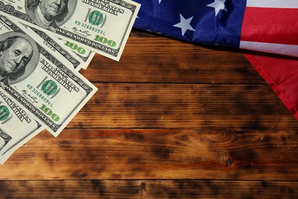 Bandera americana y cien billetes de dólar sobre fondo viejo de madera oscura. Copyspace para texto . — Foto de Stock