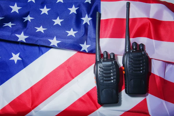 Два чорних сучасних портативних радіопередавачі з антеною на тлі американського прапора. — стокове фото