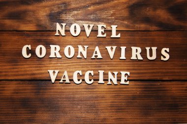 Roman Coronavirus Aşısını karanlık tahta masa arkaplanına yaz. Virüs Salgını Koruma Konsepti.