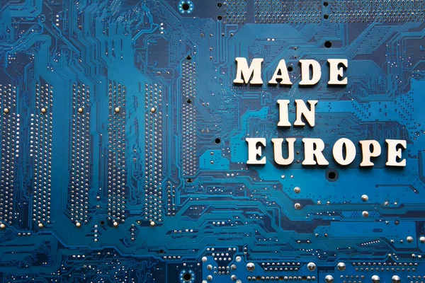 Made in Europe. Inscription on a blue printed circuit board background. Copyspace for design.