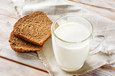 Eski beyaz ahşap masada bir bardak süt ve dilimlenmiş ekmek. Diyet yemek, sağlıklı beslenme, kilo verme kavramı. Seçici yumuşak odak