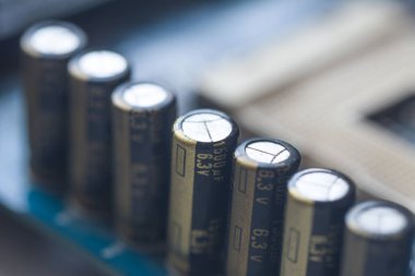 Elektrolitik kapasitörlü ana kartın bir parçası. Kapasite Meclisi. Mavi baskılı devre kartındaki elektronik bileşen kapasitörü