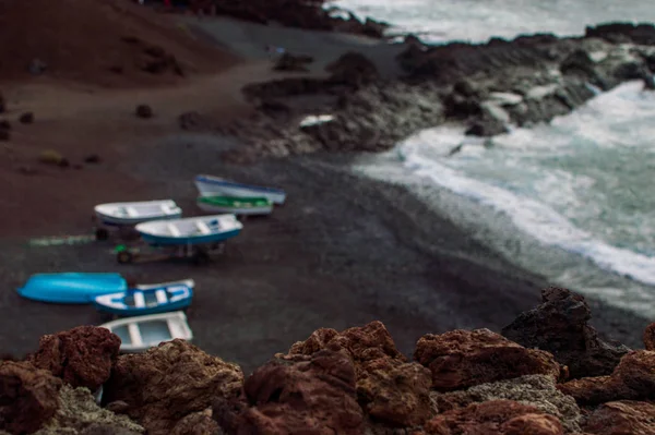 Barcos pesqueros con el océano y la playa de arena negra — Foto de Stock