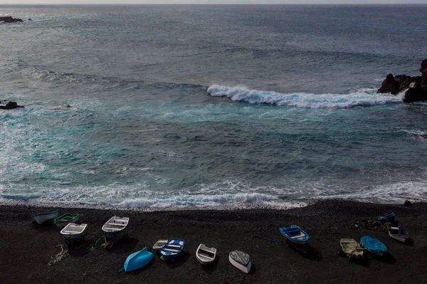 Barcos pesqueros con el océano y la playa de arena negra — Foto de Stock