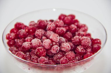 Beyaz zemin üzerinde cam bir plaka içinde donmuş kırmızı üzümler.