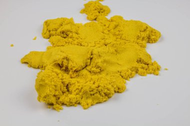 Sarı kinetik kum beyaz bir masaya saçılmış.