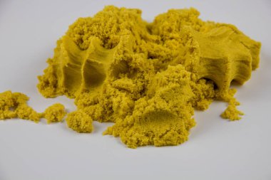 Sarı kinetik kum beyaz bir masaya saçılmış.