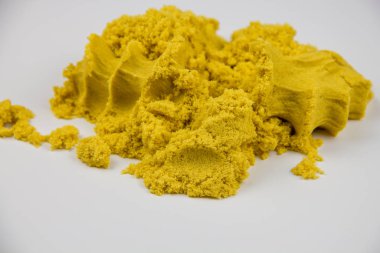 Sarı kinetik kum beyaz bir masaya saçılmış.