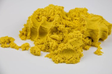 Sarı kinetik kum beyaz bir masaya saçılmış.