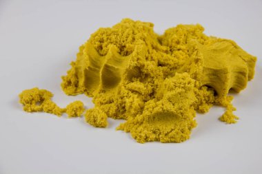 Sarı kinetik kum beyaz bir masaya saçılmış.