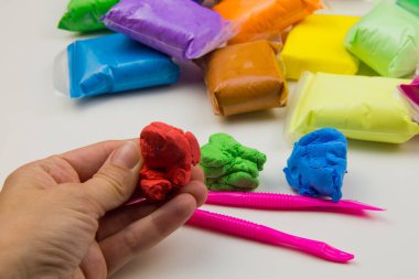 Beyaz arka planda renkli süper hafif plastik modelleme için havadar plastik kütle. Eller plastikle yontulmuş.