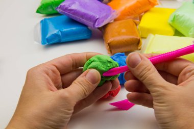 Beyaz arka planda renkli süper hafif plastik modelleme için havadar plastik kütle. Eller plastikle yontulmuş.