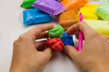 Beyaz arka planda renkli süper hafif plastik modelleme için havadar plastik kütle. Eller plastikle yontulmuş.