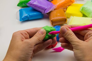 Beyaz arka planda renkli süper hafif plastik modelleme için havadar plastik kütle. Eller plastikle yontulmuş.