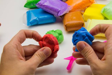 Beyaz arka planda renkli süper hafif plastik modelleme için havadar plastik kütle. Eller plastikle yontulmuş.