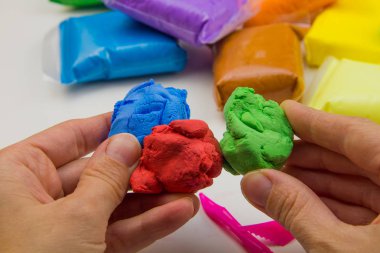 Beyaz arka planda renkli süper hafif plastik modelleme için havadar plastik kütle. Eller plastikle yontulmuş.