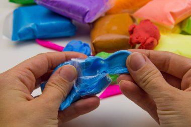 Beyaz arka planda renkli süper hafif plastik modelleme için havadar plastik kütle. Eller plastikle yontulmuş.