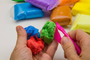 Beyaz arka planda renkli süper hafif plastik modelleme için havadar plastik kütle. Eller plastikle yontulmuş.