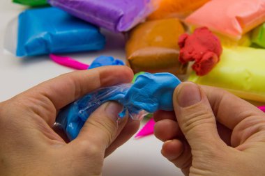 Beyaz arka planda renkli süper hafif plastik modelleme için havadar plastik kütle. Eller plastikle yontulmuş.