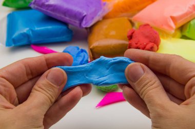 Beyaz arka planda renkli süper hafif plastik modelleme için havadar plastik kütle. Eller plastikle yontulmuş.