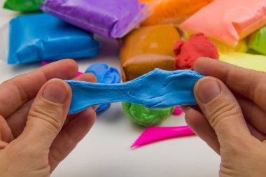 Beyaz arka planda renkli süper hafif plastik modelleme için havadar plastik kütle. Eller plastikle yontulmuş.