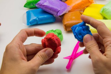 Beyaz arka planda renkli süper hafif plastik modelleme için havadar plastik kütle. Eller plastikle yontulmuş.