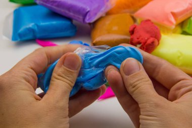 Beyaz arka planda renkli süper hafif plastik modelleme için havadar plastik kütle. Eller plastikle yontulmuş.