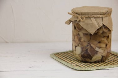 Kavanozda mayalanmış mantar konservesi ve hafif ahşap arka plan.