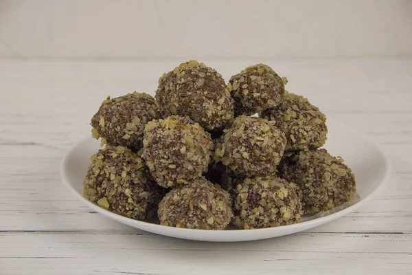 Energy balls homemade healthy candy without sugar in a white plate on a white-wooden background