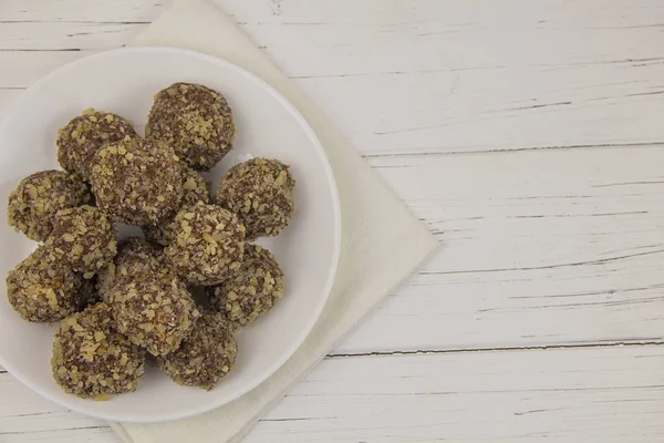 Energy balls homemade healthy candies without sugar in a white plate on a cotton napkin on a white wooden background