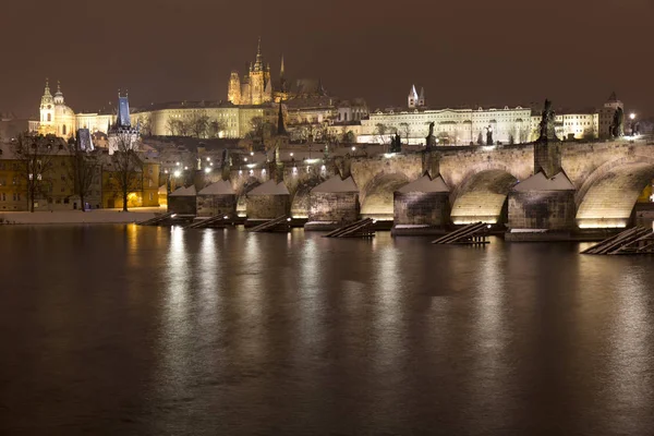 Night snowy Prague Lesser Town with gothic Castle, St. Nicholas' Cathedral and Charles Bridge, Czech republic — Stock Photo, Image