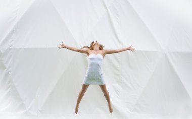 Atlama beyaz elbiseli kız. Beyaz arka plan.