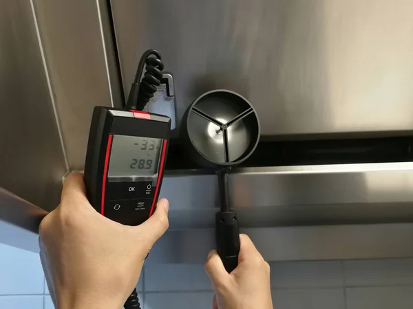 Müfettişler mutfaktaki kaputun hava hızını ölçmek için anemometre kullanıyorlar..