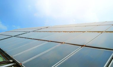 Güneş ışığı ve mavi gökyüzü ile birlikte Bina 'da sıcak su temini için Güneş Isısı - Enerji tasarrufu kavramı