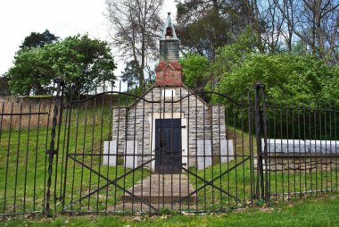 Çan kulesi, mezar taşı ve işlenmiş demir çitlerle bir tepenin kenarına inşa edilmiş çok eski bir mozole.