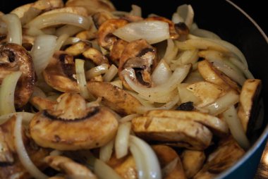Kızartma tavasında sotelenmiş mantar ve soğan yağlı, baharatlı ve buharlı.
