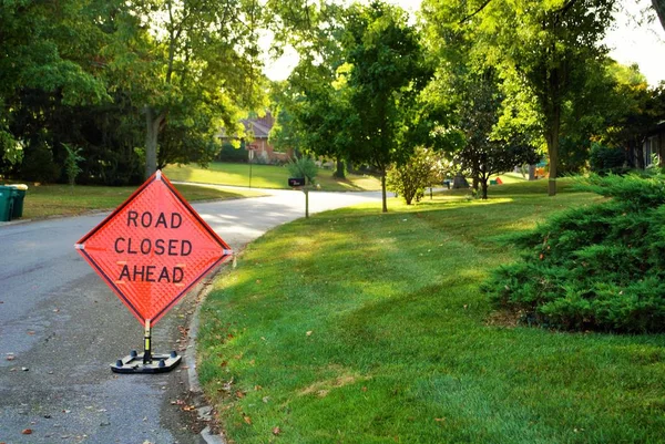 road closed ahead construction sign in a residential neighborhood