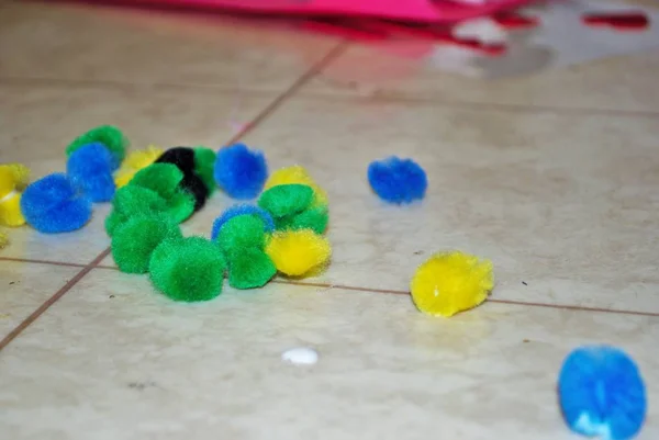 Multi colored cotton balls and glue on a linoleum floor during arts and crafts time