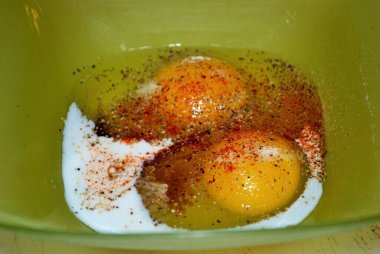 Yeşil plastik bir kasede iki çiğ yumurta yakın.