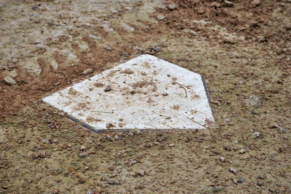 dirt covered home plate from a deserted baseball diamond