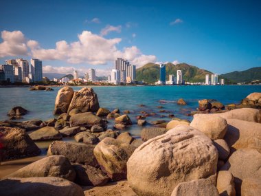 Okyanustaki kayalar. Arkasında dağlar olan büyük bir şehir