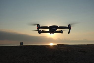 İHA gün doğumunda sahilde uçuyor.